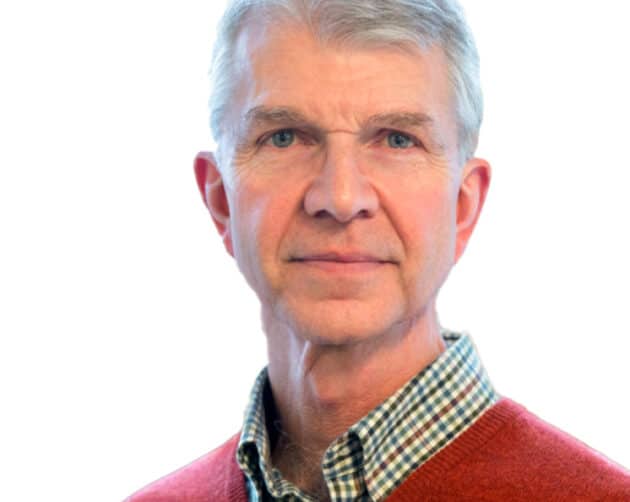 A man with gray hair is wearing a red sweater over a checkered shirt. The background is plain white. ©Mobysoft