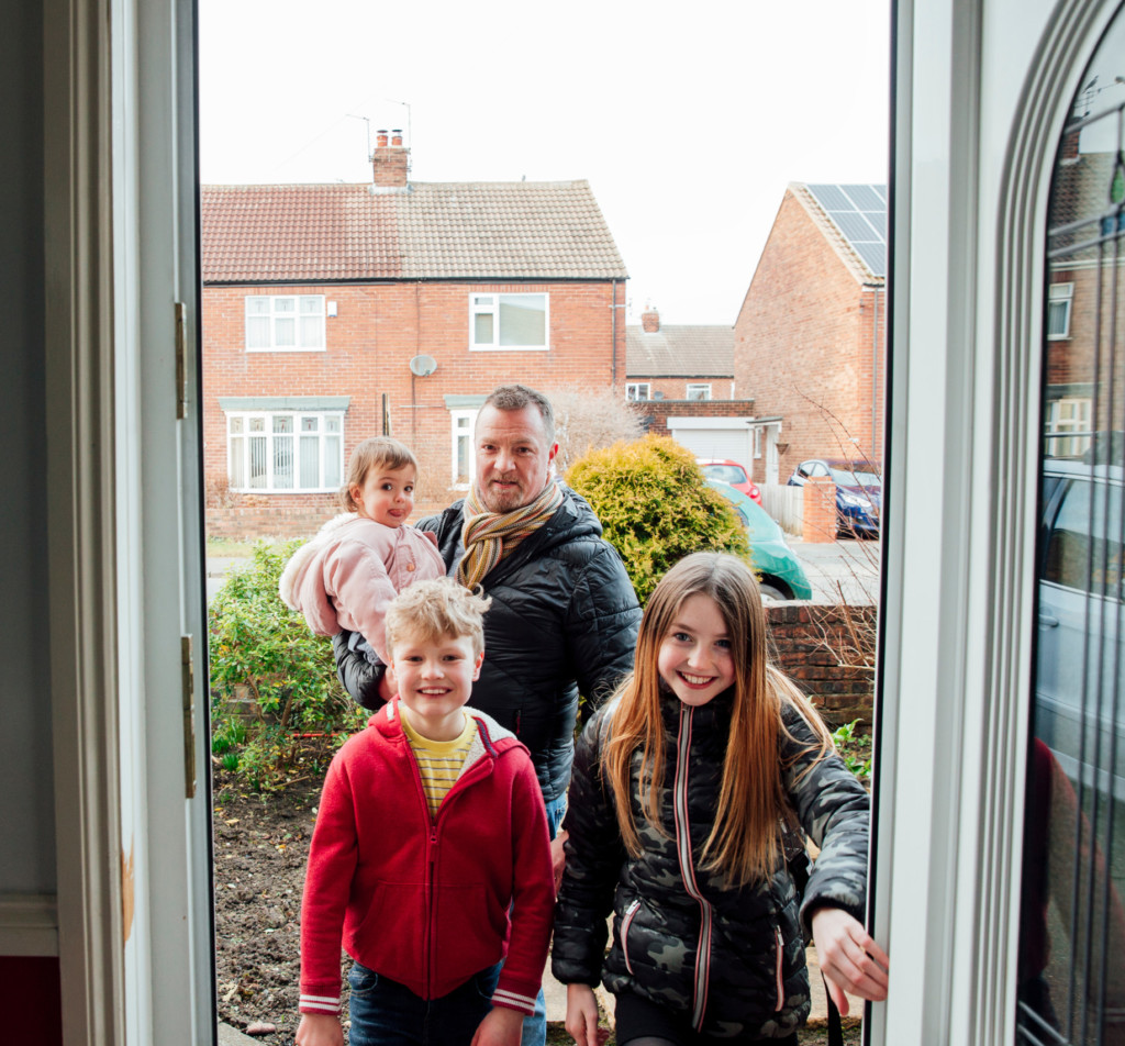 Family entering front door of home cropped