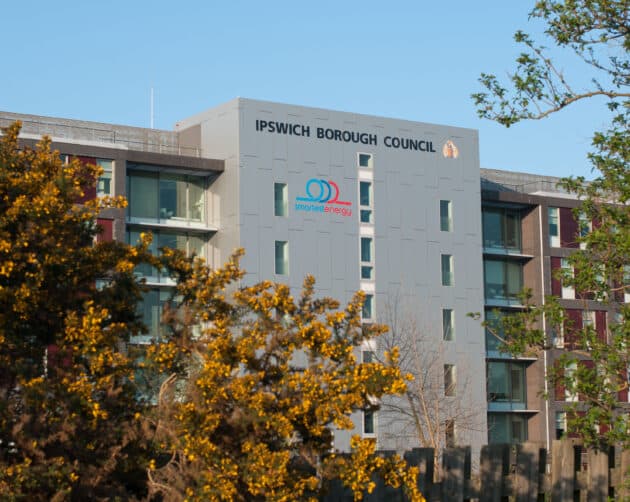 A modern building with the "Ipswich Borough Council" sign is partially obscured by lush trees. The facade proudly bears a "smarter working" logo, under a clear blue sky. ©Mobysoft